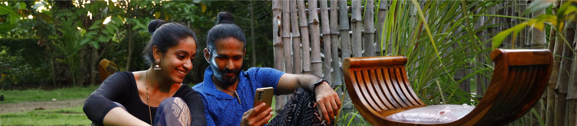 A happy couple sitting on a green lawn and viewing mobile